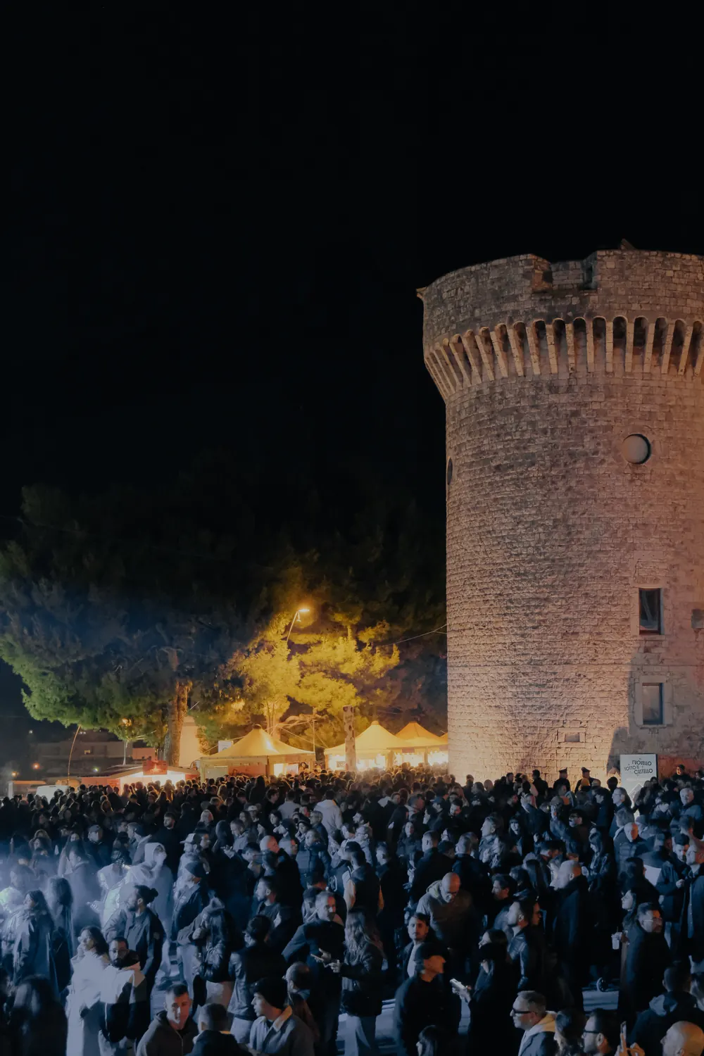 La torre del castello illuminata e la folla in piazza